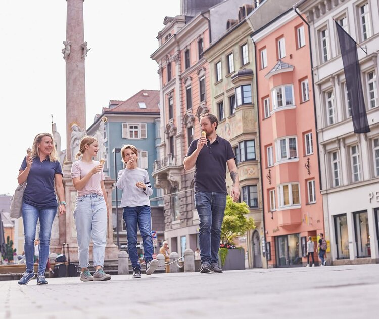 Familie mit 2 Kindern isst ein Eis und spaziert durch die Maria-Theresien-Straße