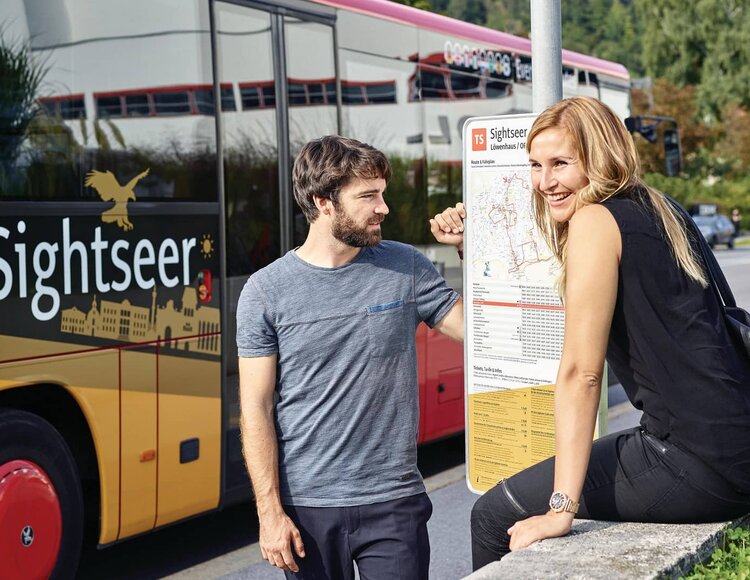 Ein Mann und eine Frau an einer Bushaltestelle.