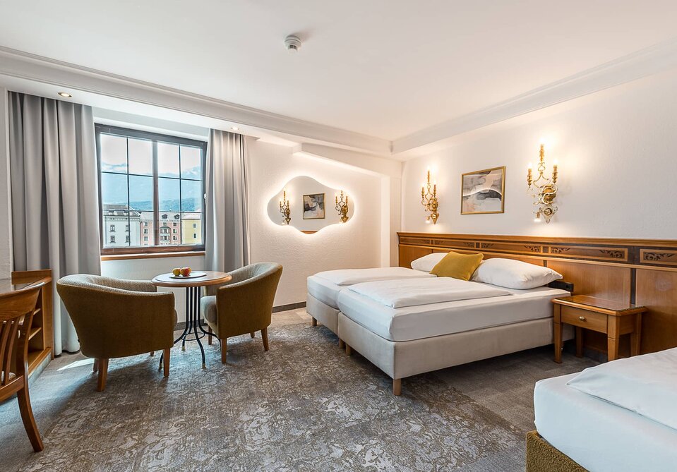 Ein Hotelzimmer mit Doppelbett, Tisch und zwei Sessel.