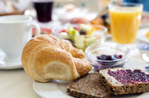 Ein Marmeladenbrot auf einem gedeckten Frühstückstisch.