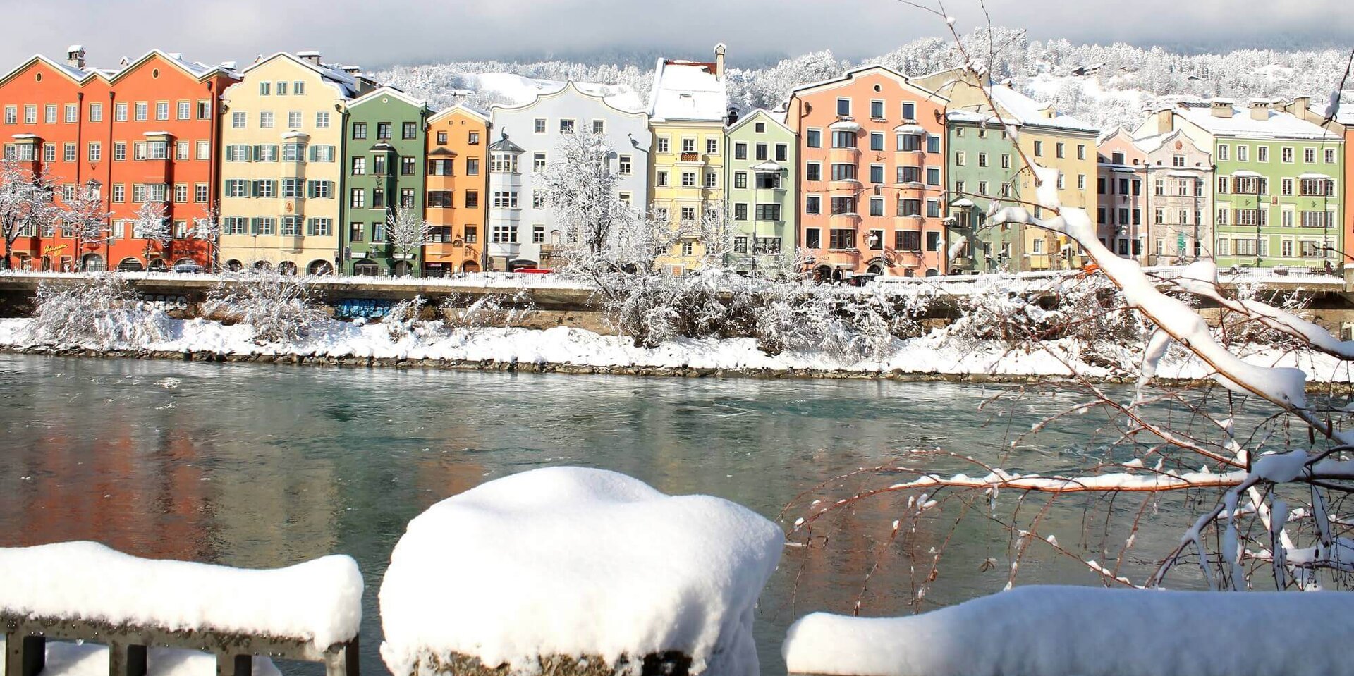 Bunte Häuserzeile am Fluss Inn schneebedeckt