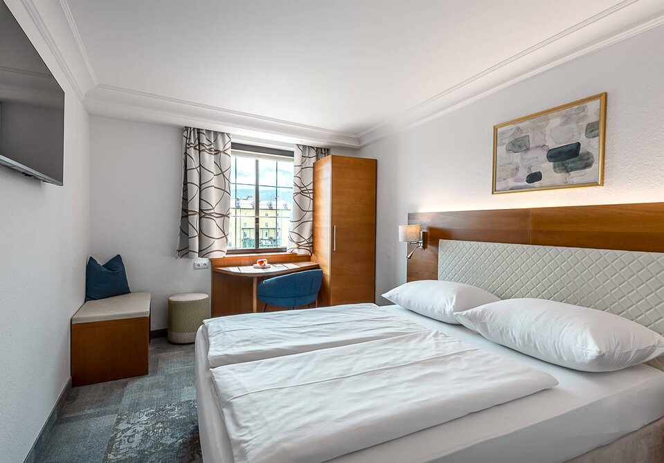 Hotelzimmer mit Doppelbett und Fernseher