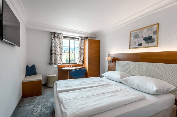 Hotelzimmer mit Doppelbett und Fernseher